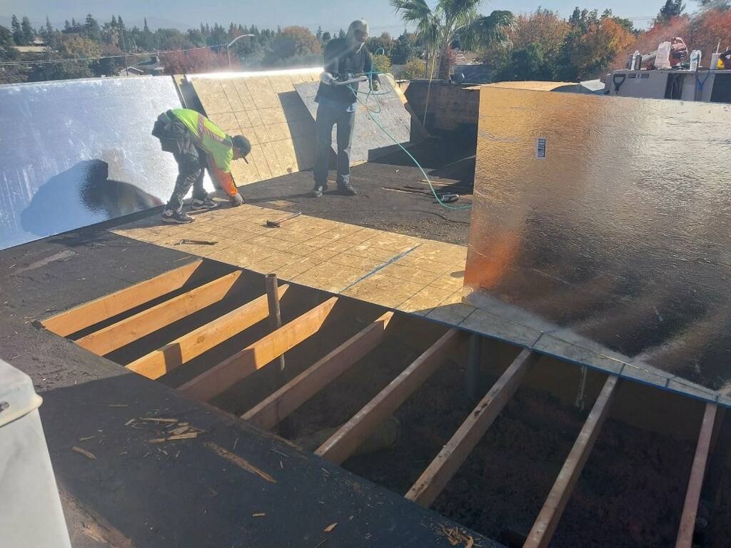 Trabajadores colocando paneles de madera sobre la estructura del techo